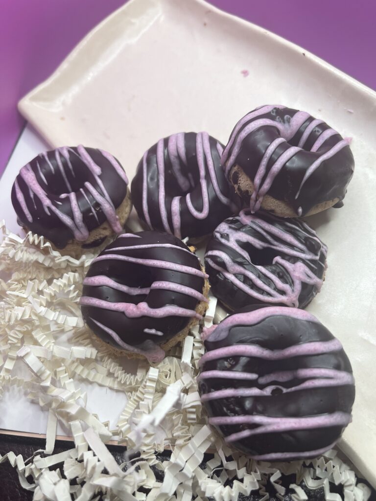 A Box of Assorted Donuts Featuring Vibrant Purple and Pink Icing